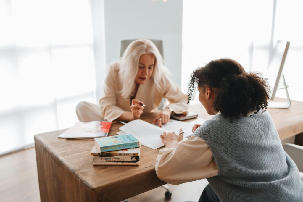 A tutor and student engaged in a learning session with books and notes on a table.